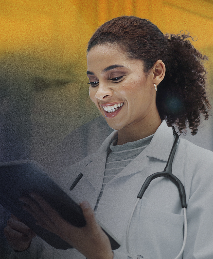Médica sorrindo, vestindo scrub azul e estetoscópio, segurando um tablet